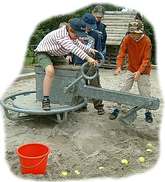 Using a sand pit digger truck little balls must be dug out of the sand and poured into a bucket.